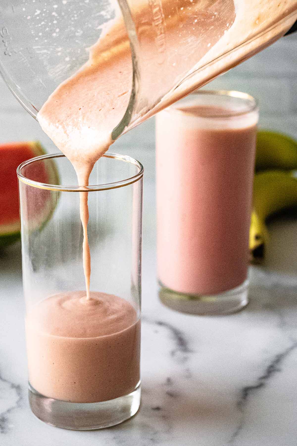 Watermelon banana smoothie being poured into a tall chilled glass