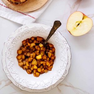 Overhead view of apple compote in a white bowl with a spoon