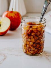 Small open mason jar filled with apple compote. A spoon is sitting inside the jar.