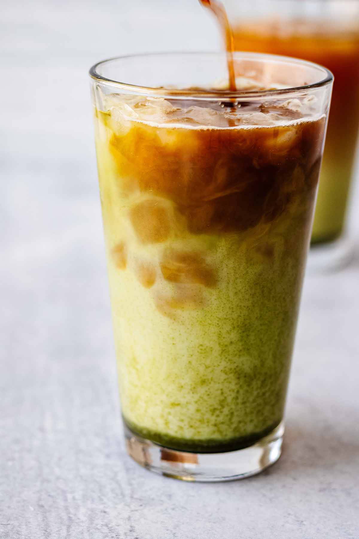 Espresso being poured into tall glass with matcha mixture