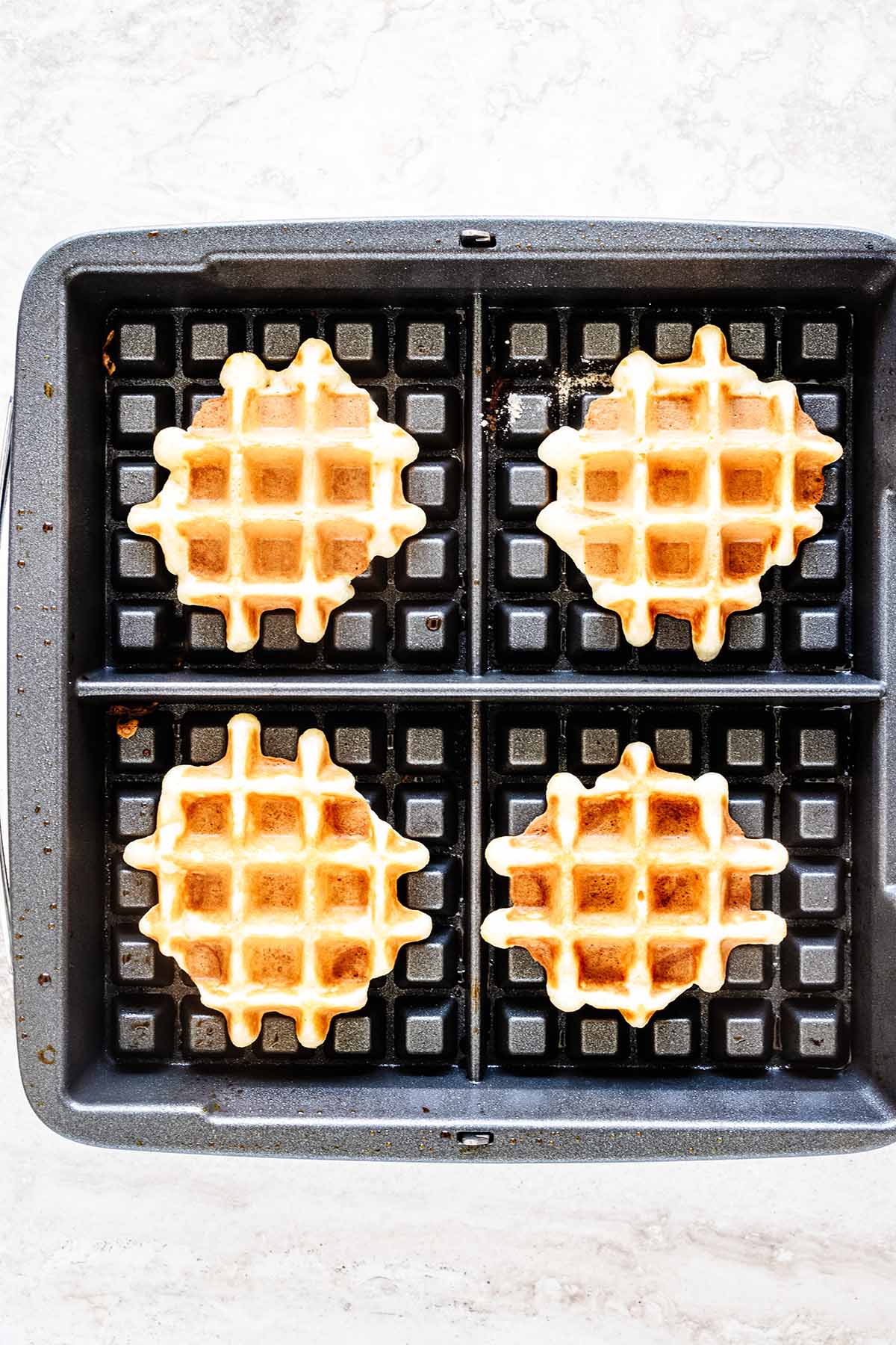 Overhead view of waffles cooking on a waffle iron
