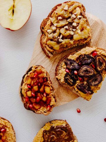Overhead view of peanut butter toast with various toppings - sliced dates, sliced bananas, chopped apples, and Nutella