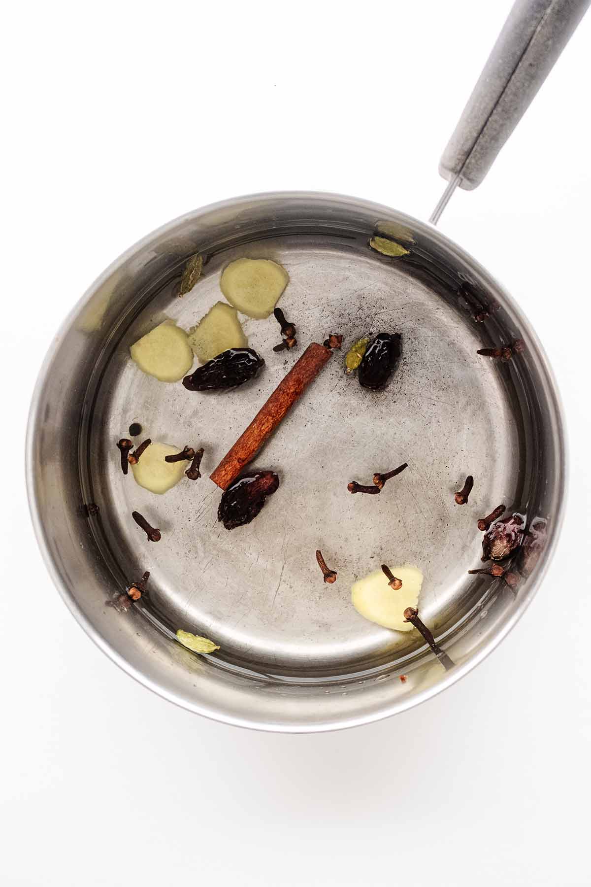 Overhead view of fresh spices in a saucepan with water