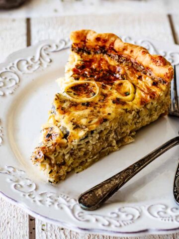 Slice of quiche on a white plate with two forks.