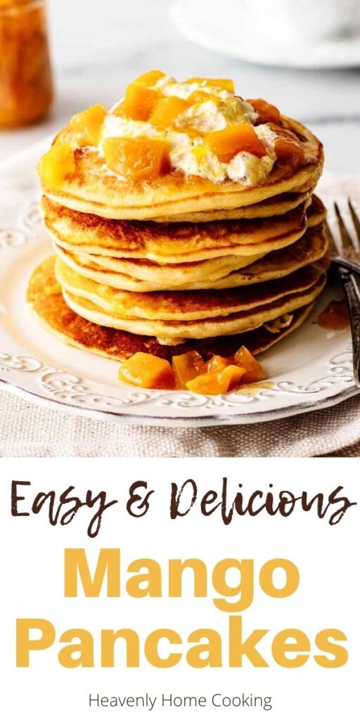 Stack of pancakes topped with whipped cream and mango compote on a white plate with two forks. A jar of fresh mango compote and hot tea in a white teacup with saucer are in the background with text overlay that says, "Easy and Delicious Mango Pancakes."