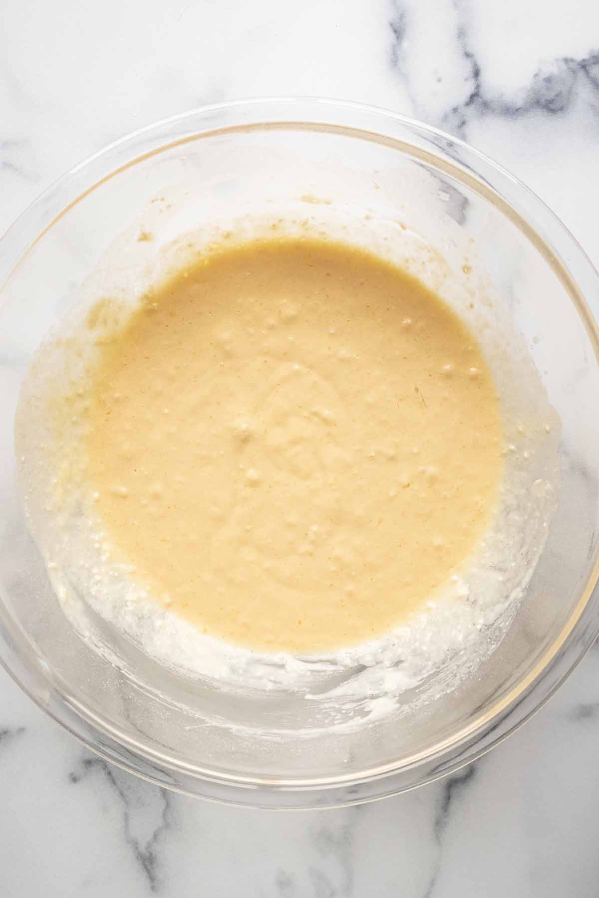 Overhead view of pancake batter in a large glass bowl.