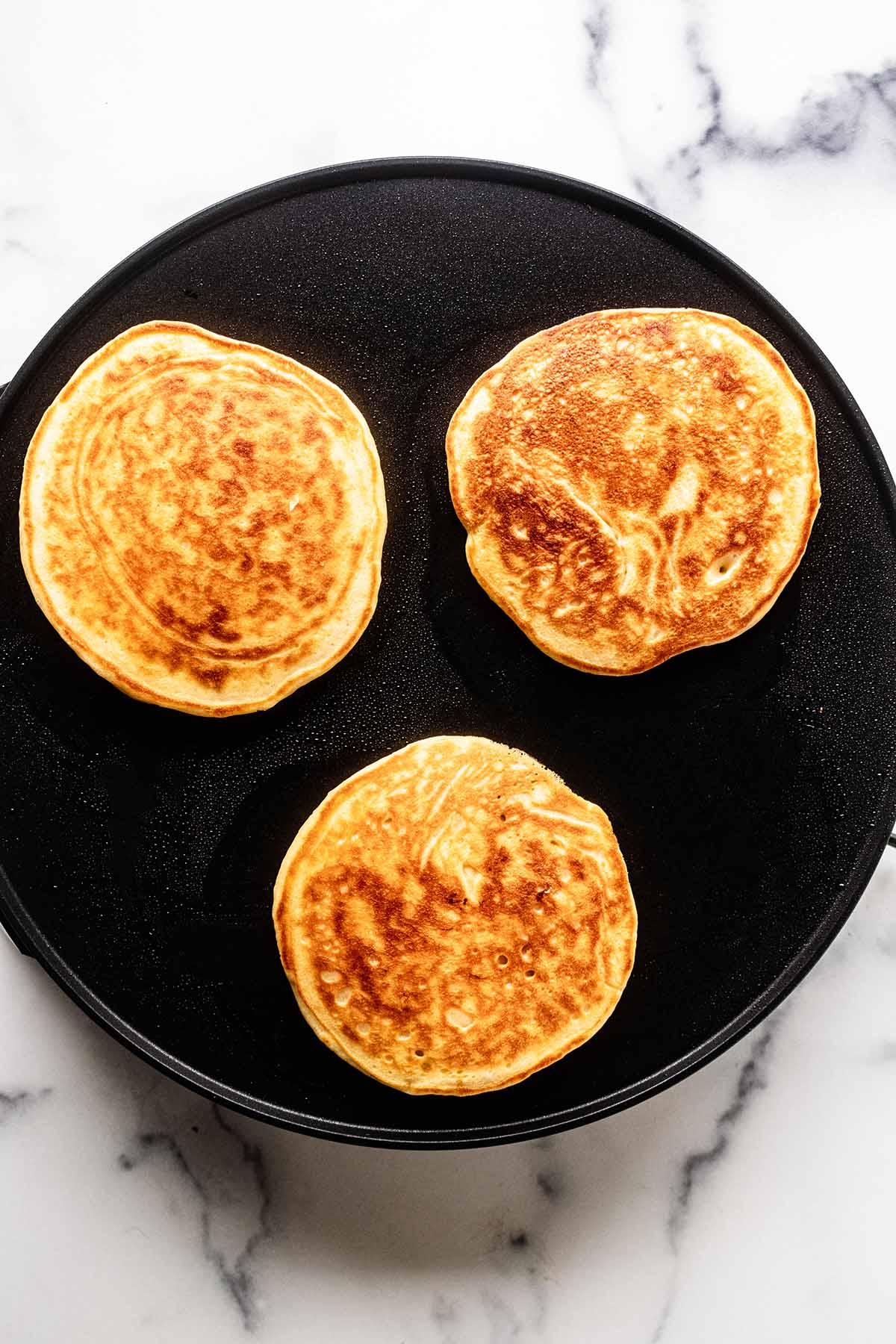 Overhead view of cooked pancakes on a griddle.