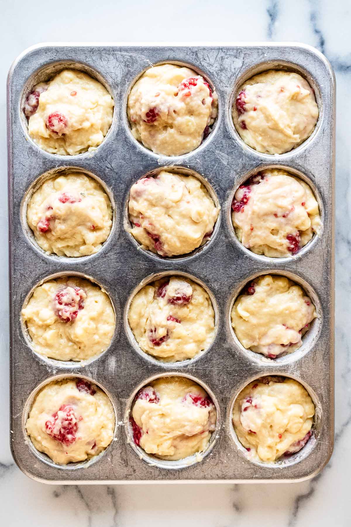 Batter evenly distributed in a 12-cup muffin pan.