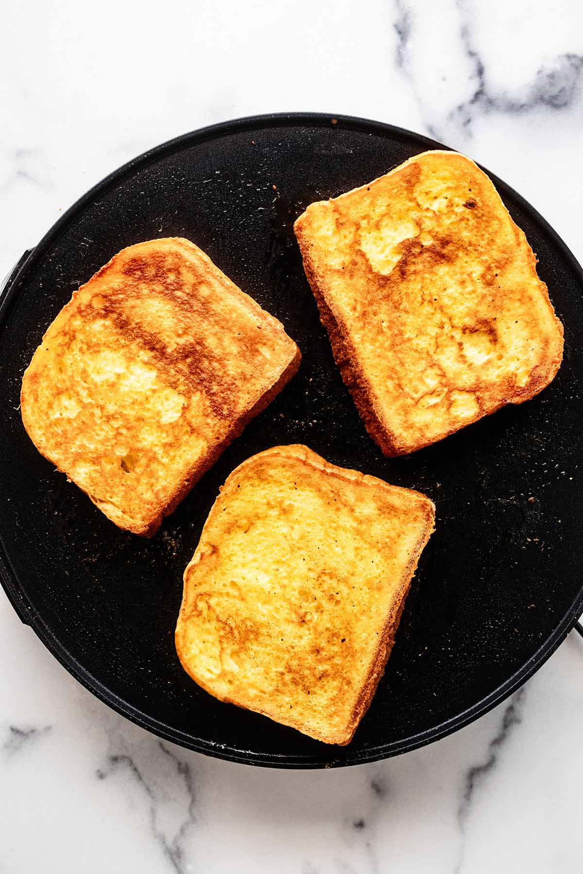 Overhead view of French toast cooking on a griddle