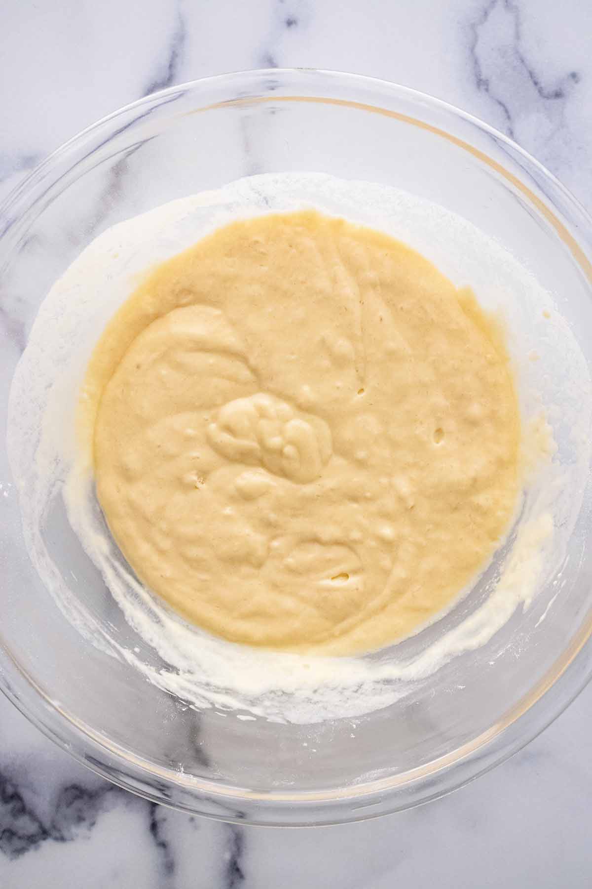 Overhead view of pancake batter in a large glass bowl