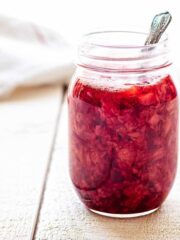 Close up of a jar of strawberry compote with a spoon