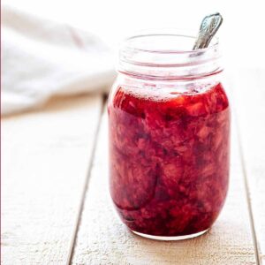 Close up of a jar of strawberry compote with a spoon
