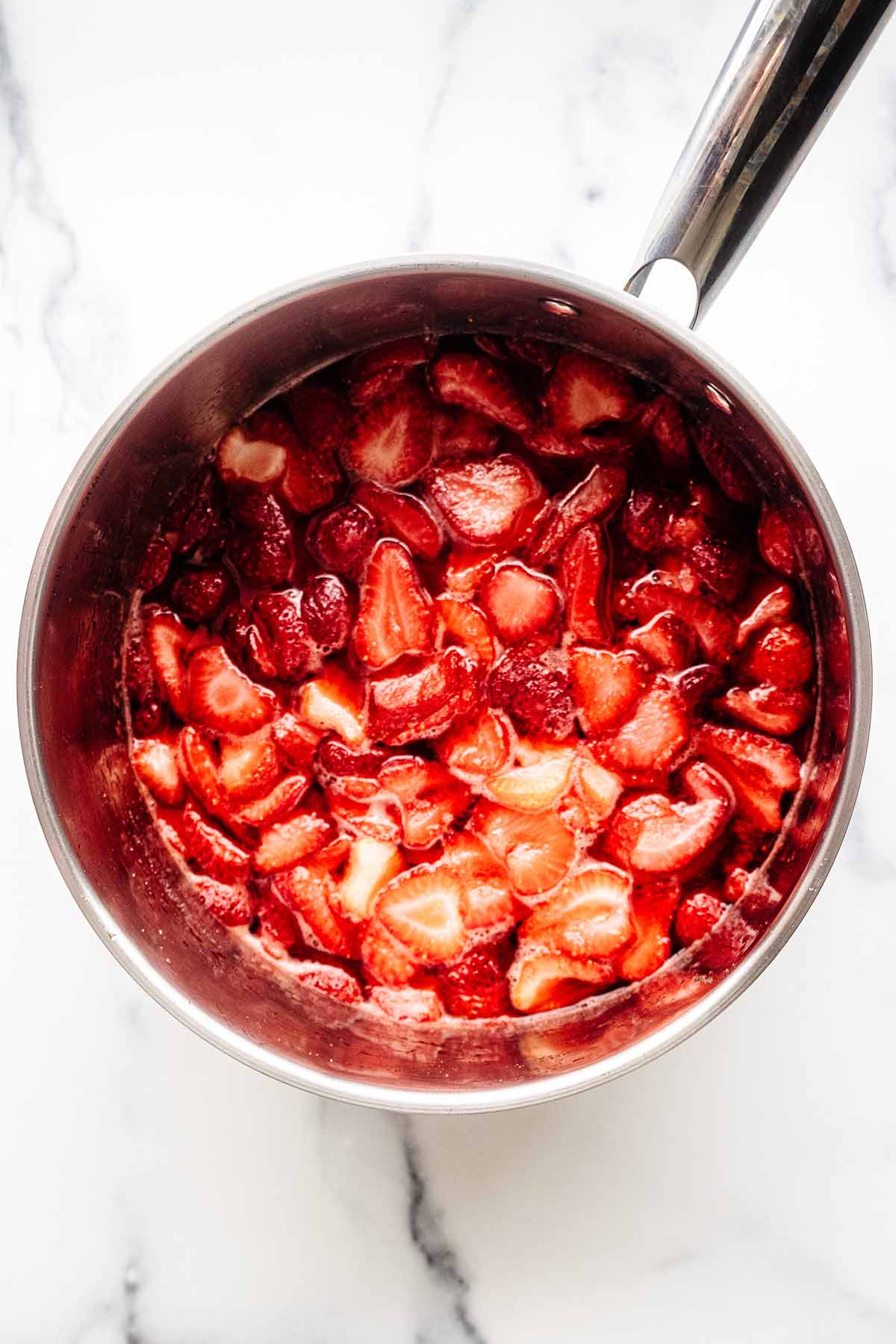 Overhead view of cooked strawberry compote in a stainless steel saucepan