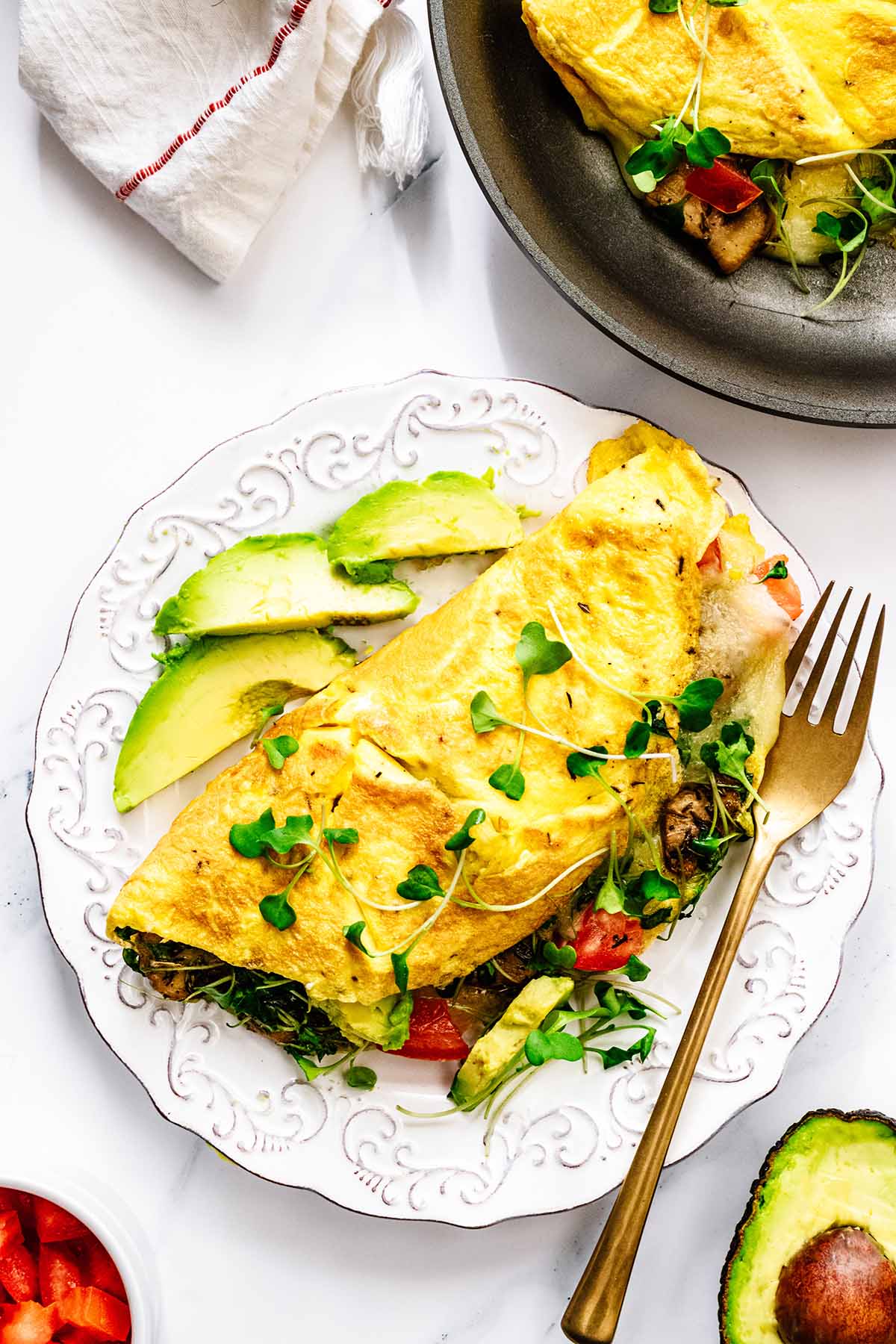 Close up overhead view of California omelette on a white plate with sliced avocado