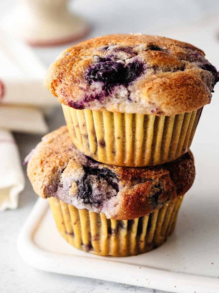 Two eggless blueberry muffins stacked on a white platter