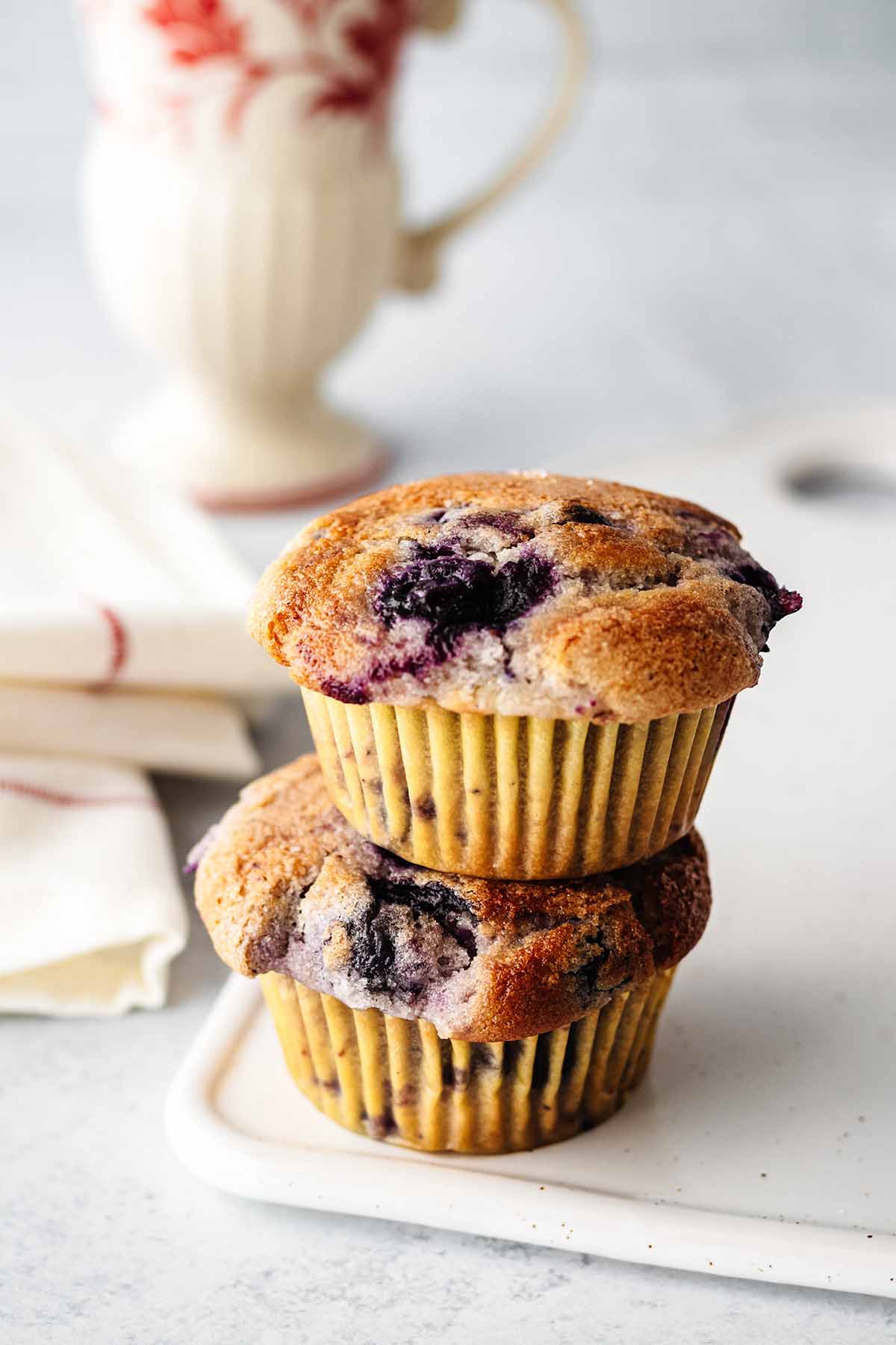 Two eggless blueberry muffins stacked on a white platter