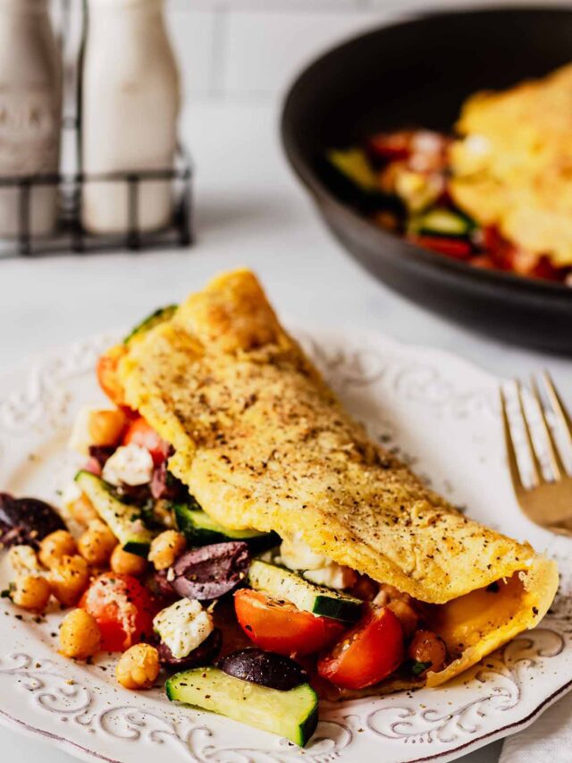 Greek Omelette with tomatoes, cucumber, chickpeas, and feta on a white plate