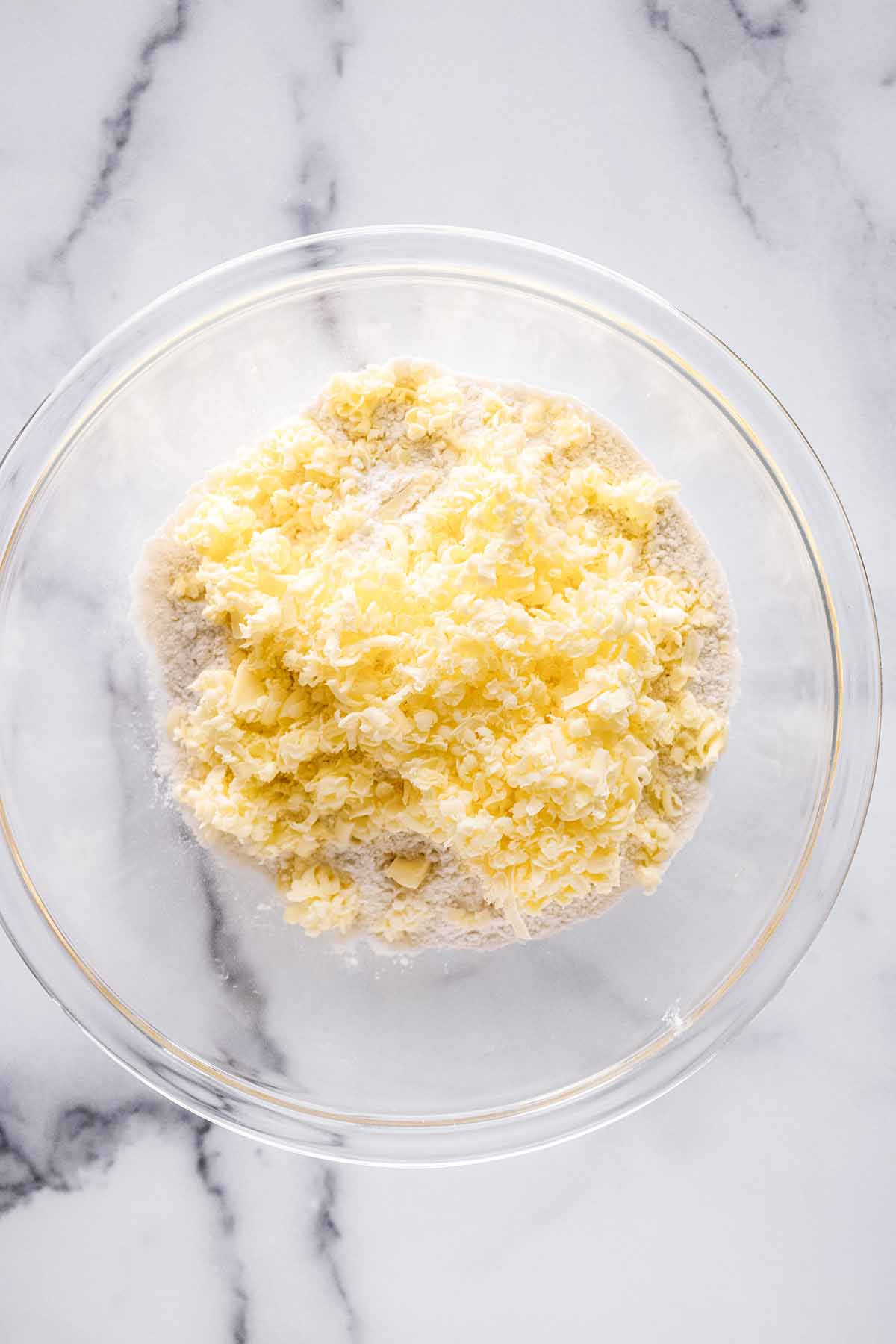 Butter and flour in a glass bowl on a marble background.