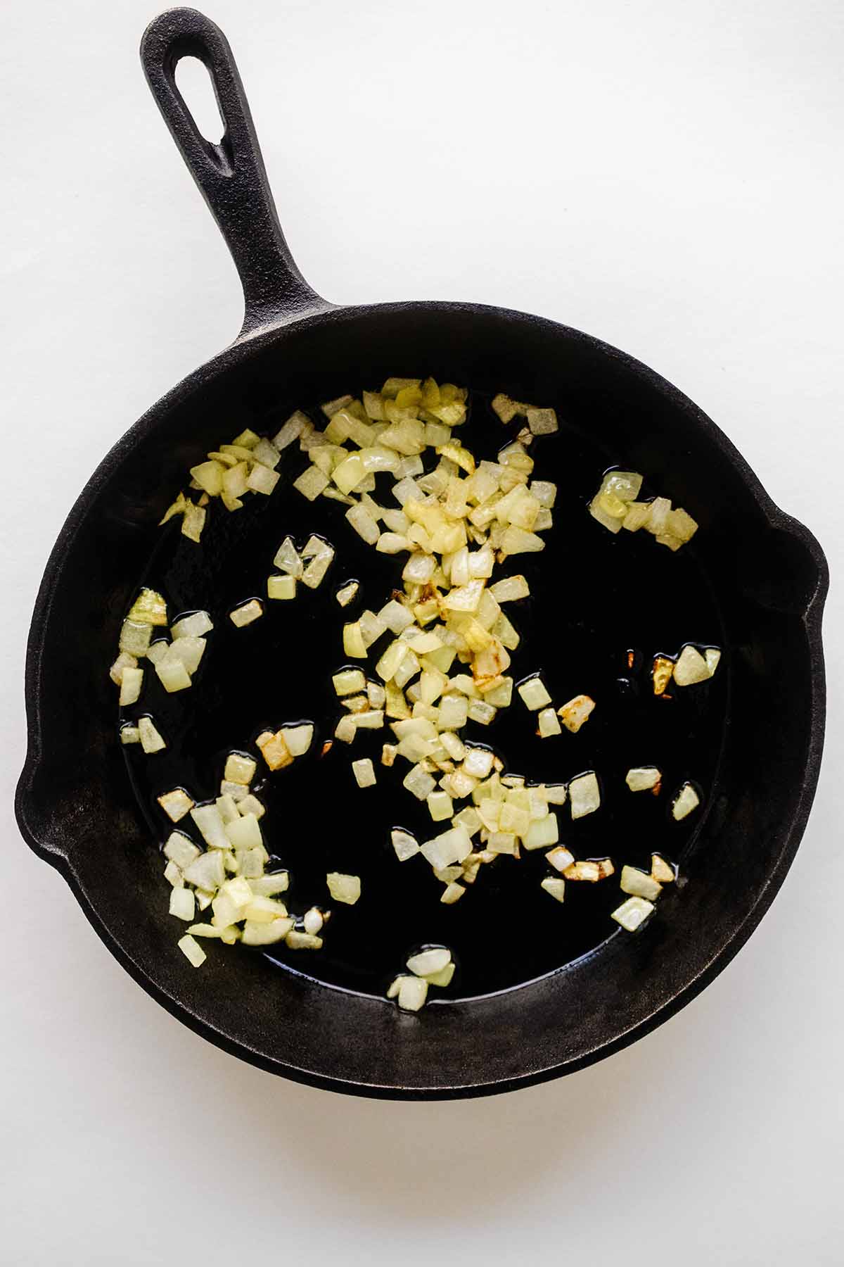 Overhead view of chopped onion cooking in a skillet.