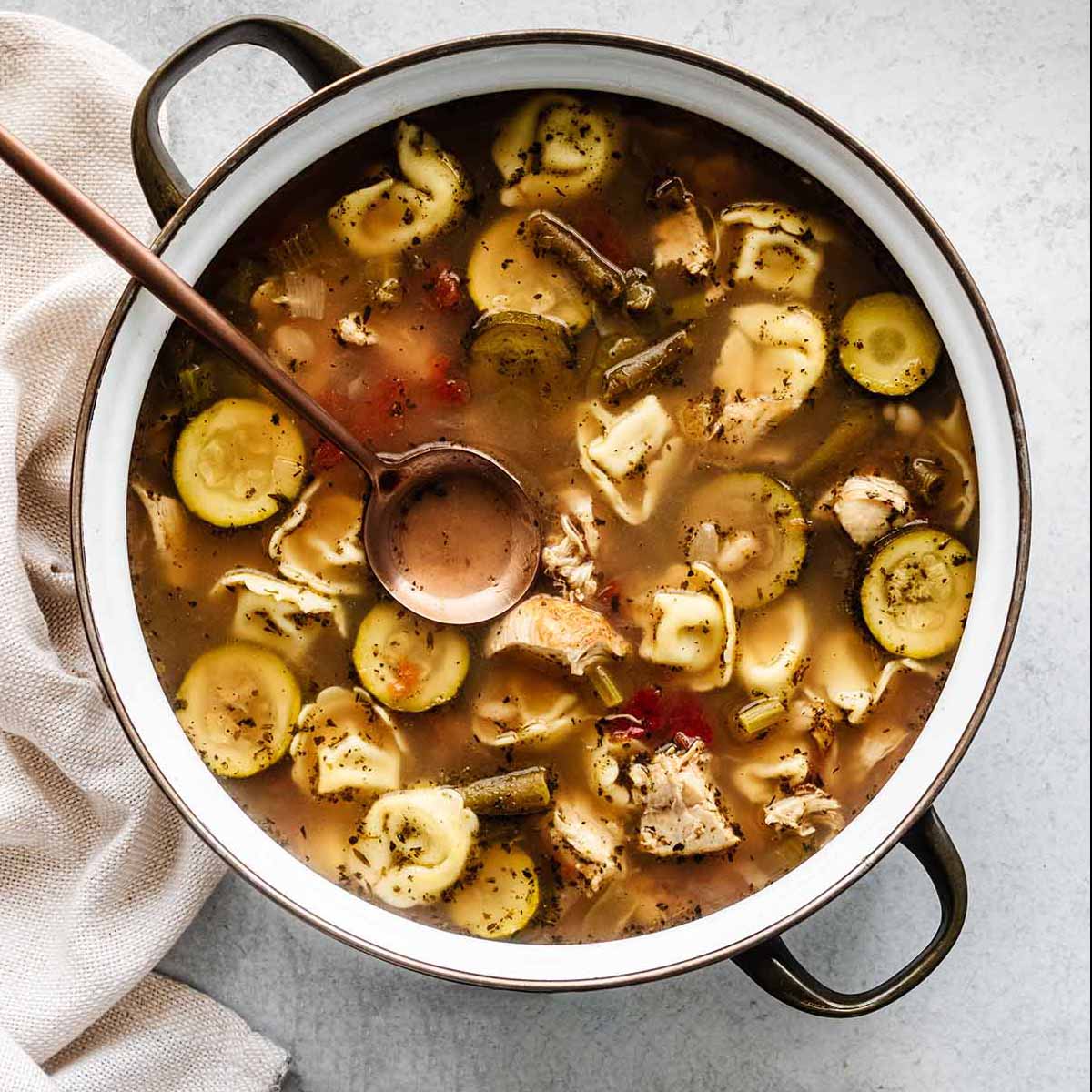 Close up of chicken tortellini crockpot soup in a large soup crock.