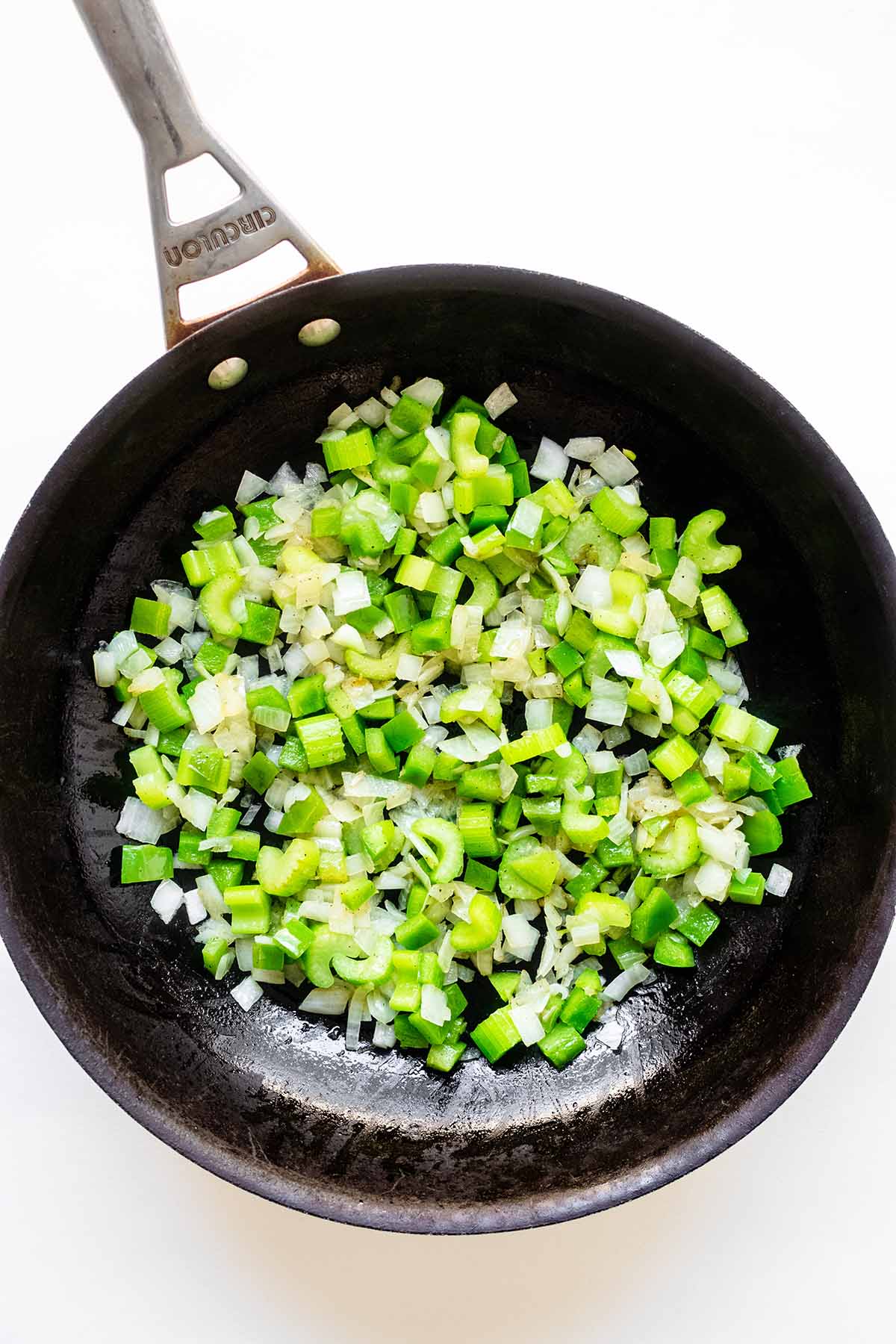 Chopped onion, bell pepper, and sliced celery in a skillet.