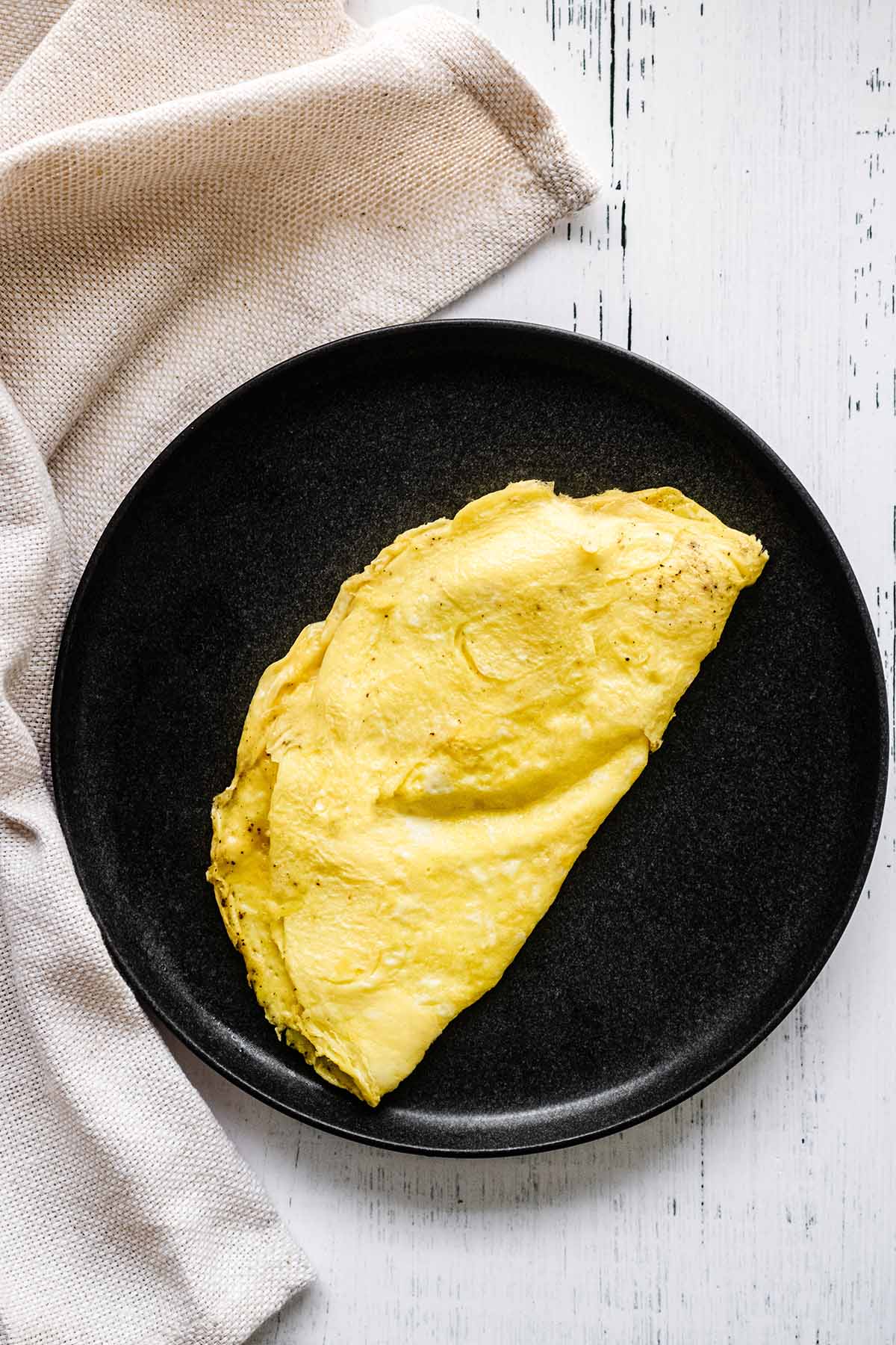 Whipped egg omelet on a dark grey plate with a beige napkin.