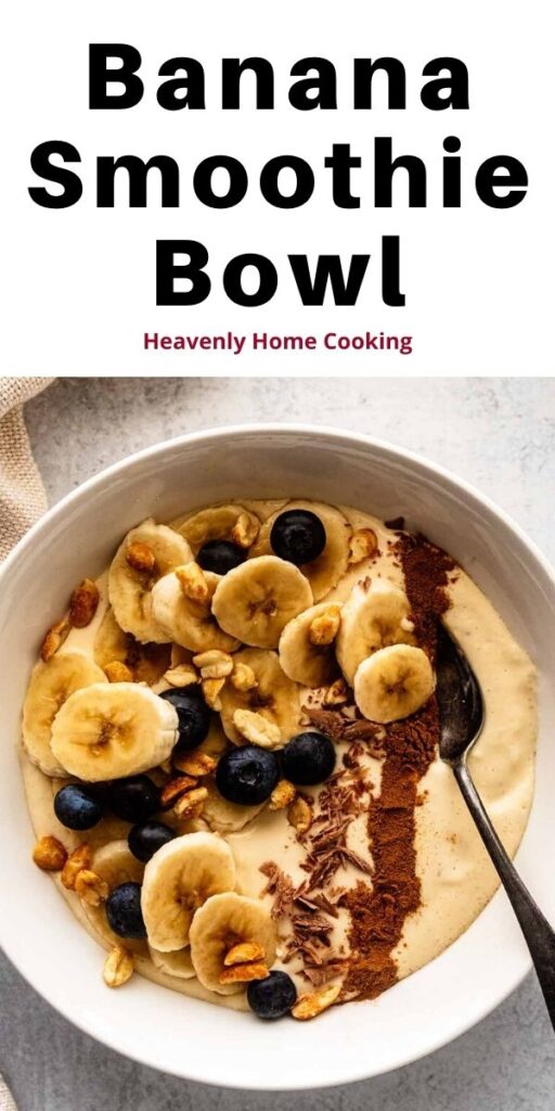 Banana smoothie bowl topped with chopped peanuts, fresh blueberries, chocolate shavings, and a line of ground cinnamon in a white bowl with a spoon.