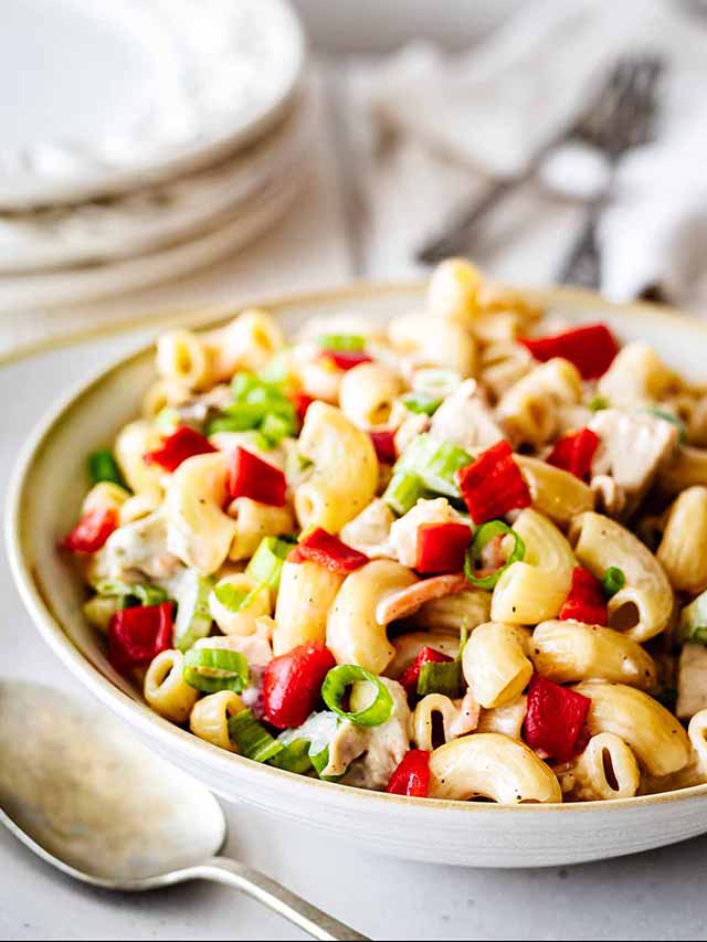 Chicken macaroni salad in a white bowl with a spoon.