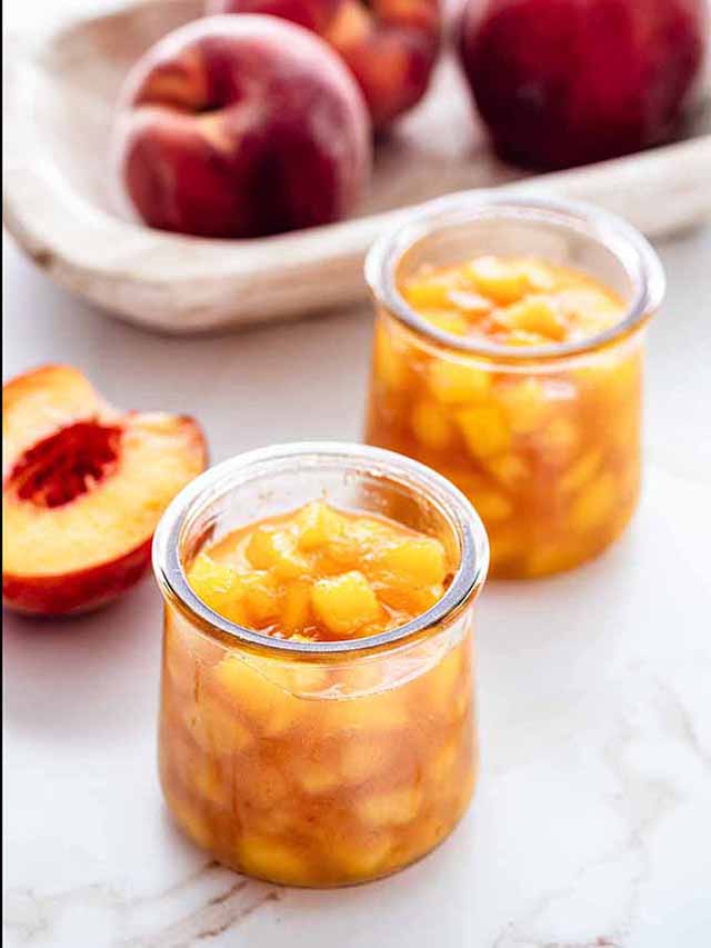 Peach compote in two small jars with peaches.