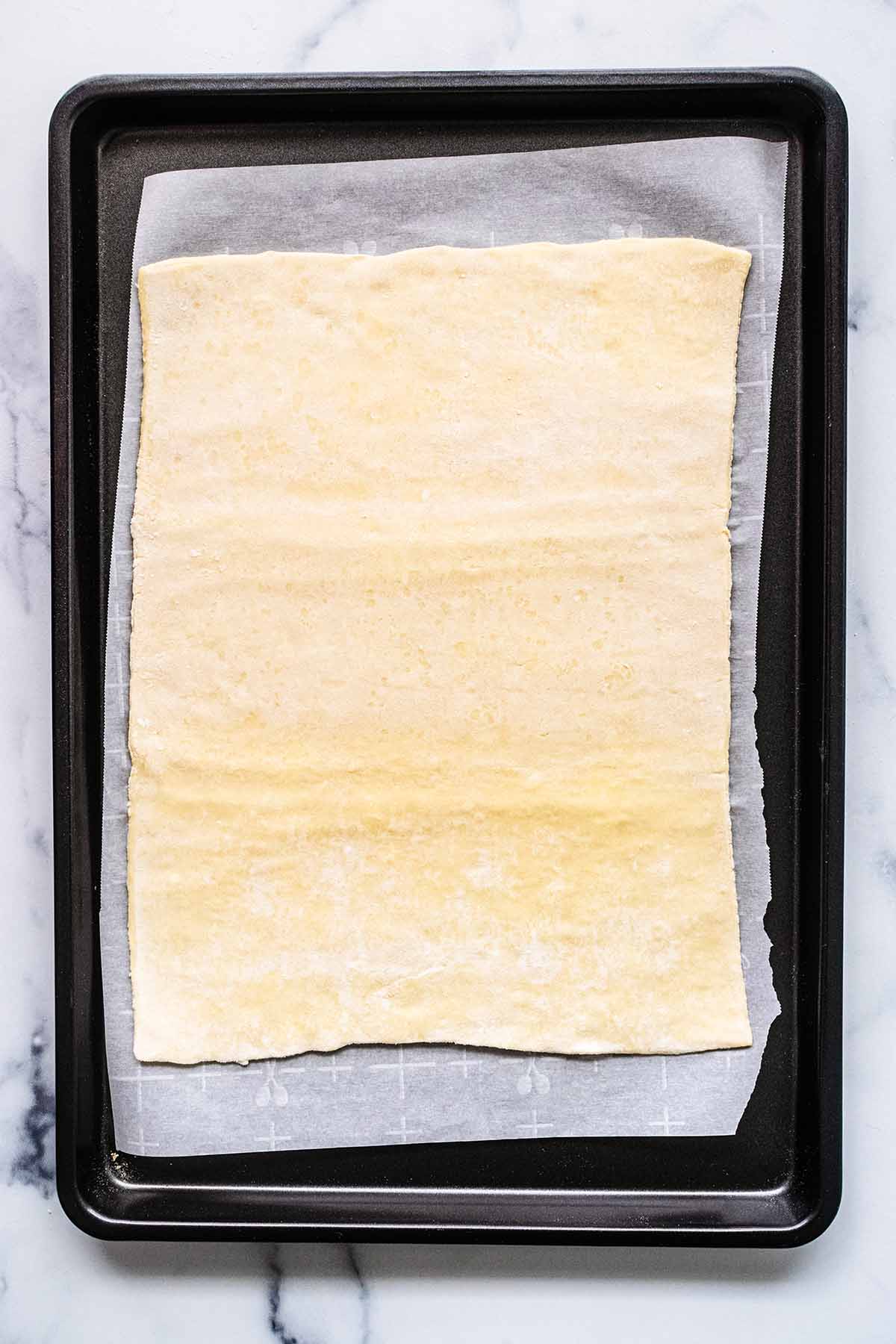 Puff pastry sheet on parchment paper in a baking sheet.