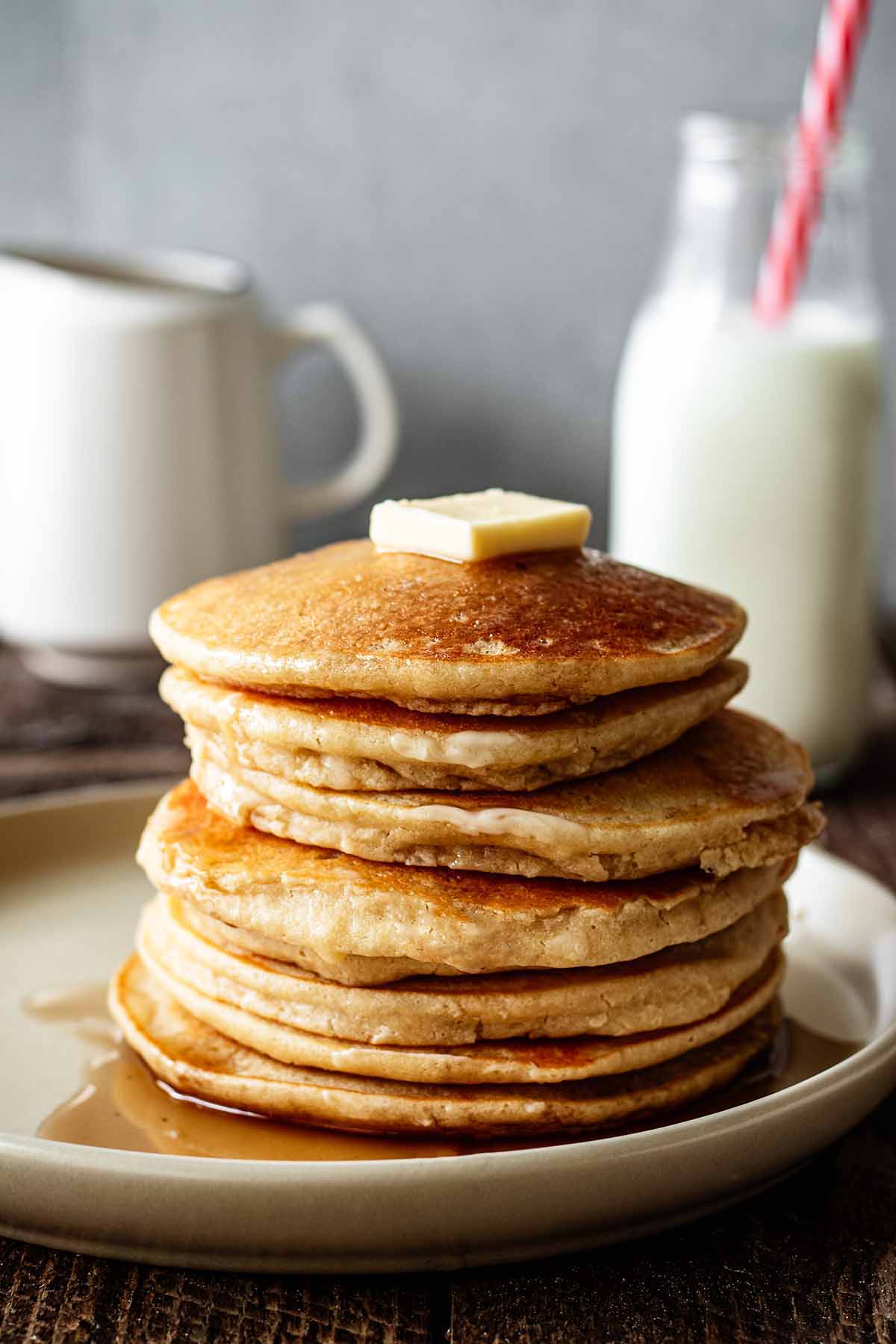 Stack of cassava pancakes on a beige plate with butter and maple syrup.