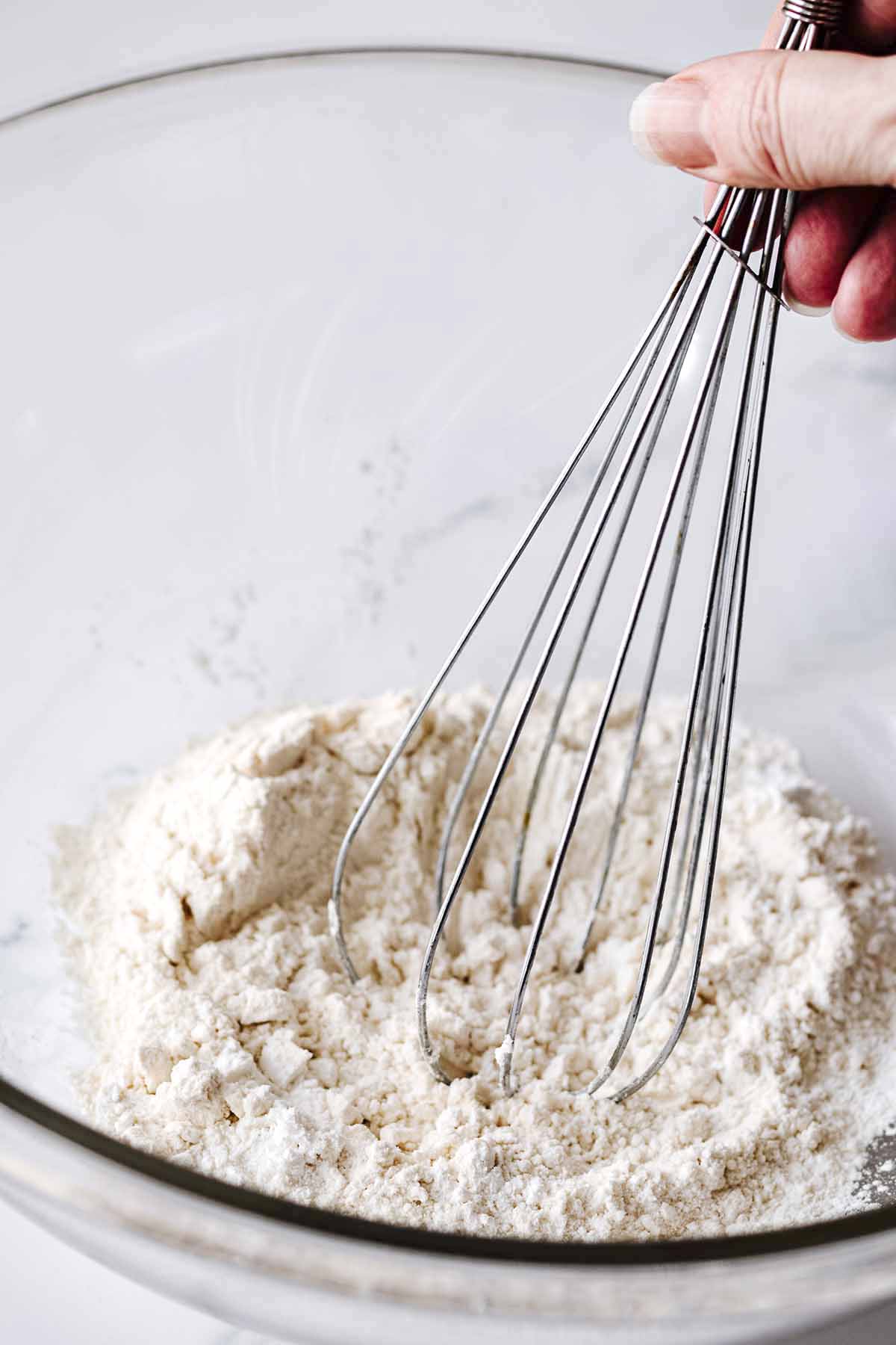 Dry ingredients in a large glass bowl with a whisk.