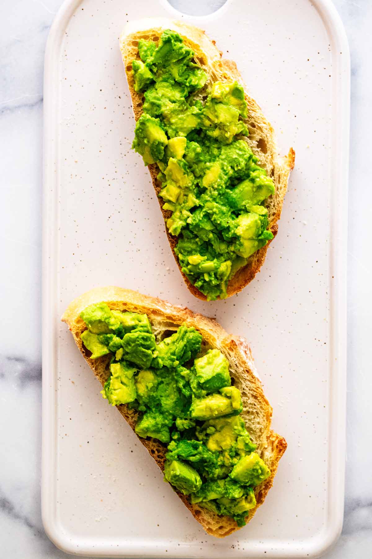 Mashed avocado mixture on two slices of toast.