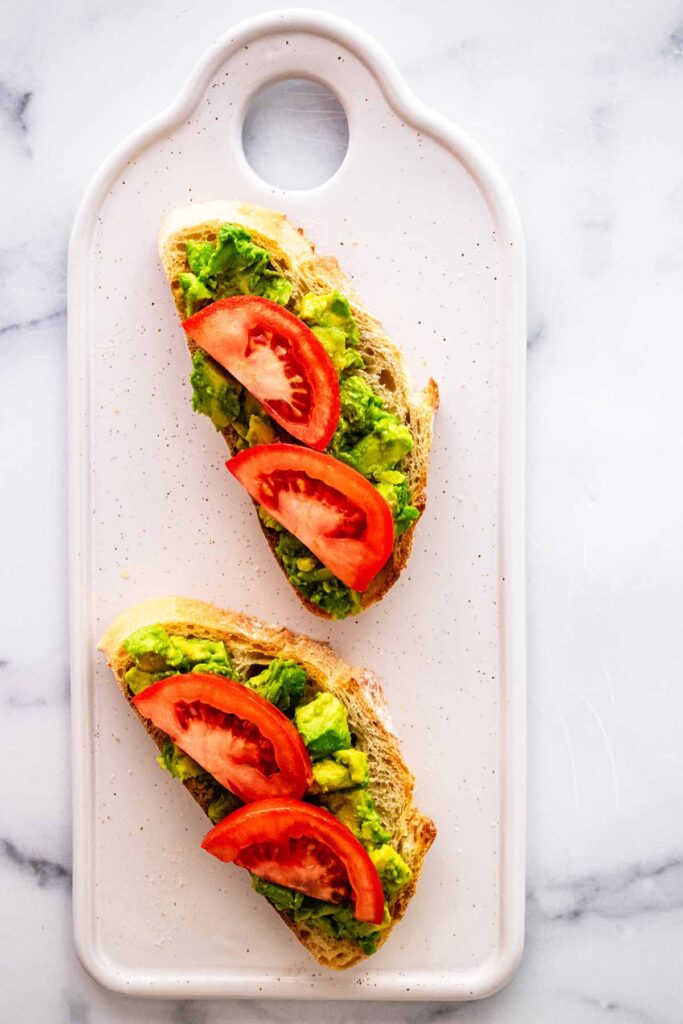 Avocado toast topped with sliced tomatoes.