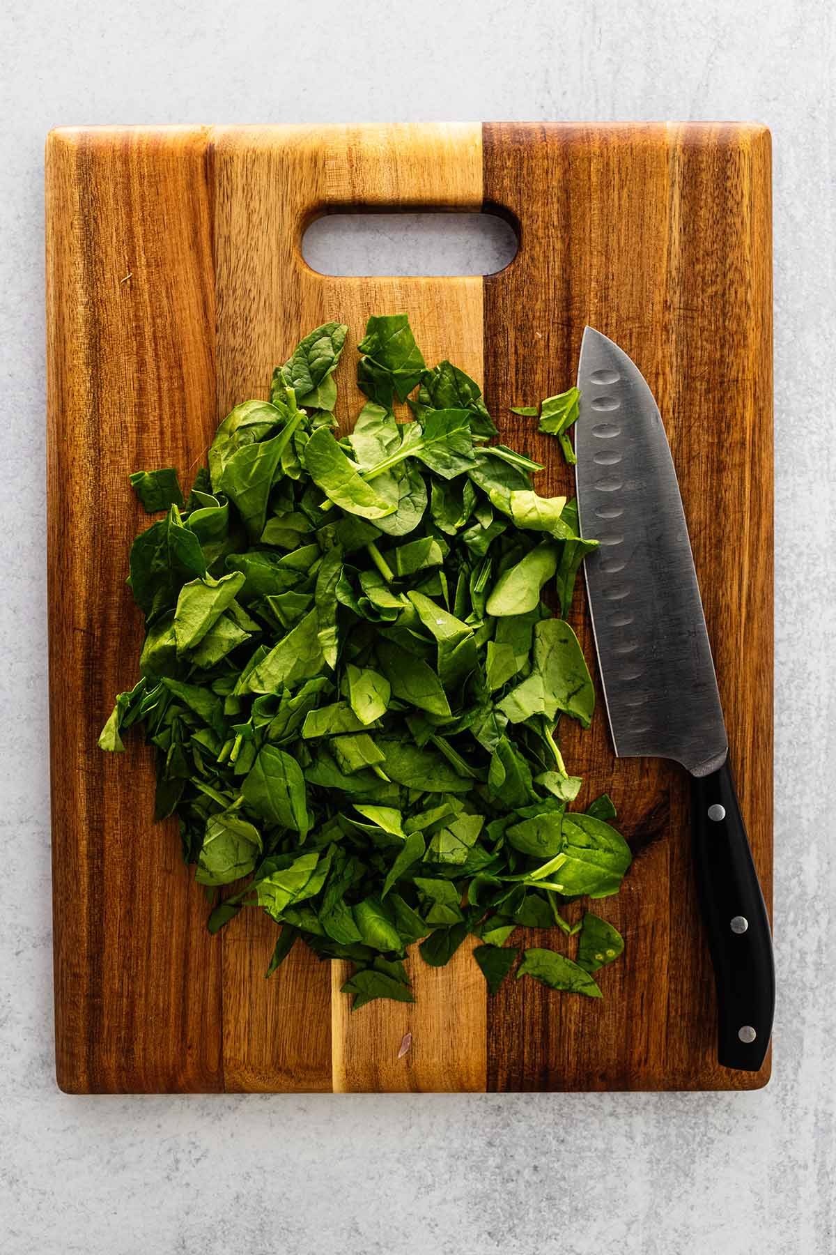 Chopped spinach on a wood cutting board.