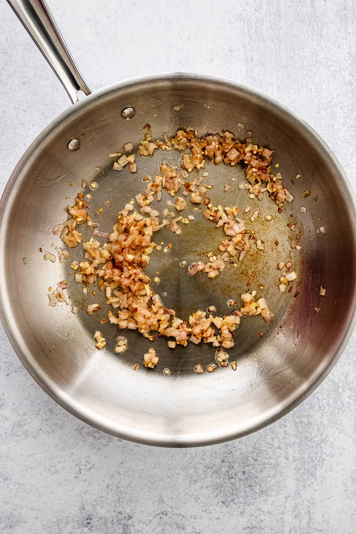 Minced garlic and cooked shallot in a skillet.