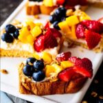 Close up of ricotta toast topped with fresh strawberries, diced mango, and whole blueberries.