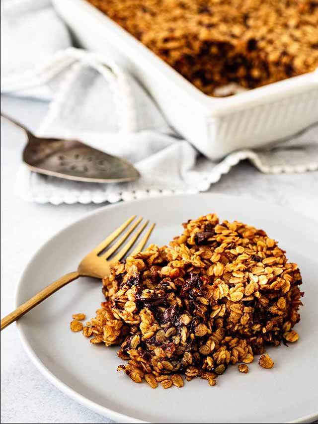 Serving of chocolate chip baked oatmeal on a light grey plate with a gold fork