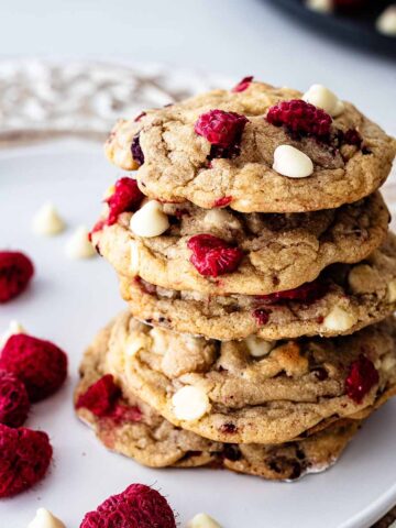 Stack of five raspberry white chocolate on a white plate with raspberries and white chocolate chips.