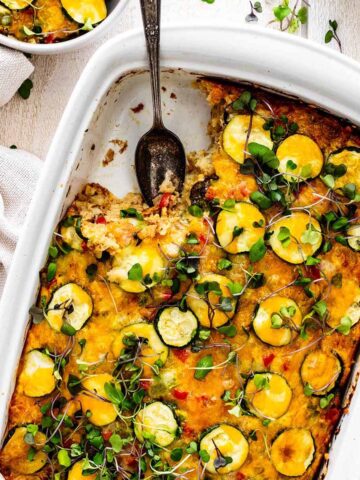 Vegetarian tater tot breakfast casserole with a serving taken out in a white ceramic baking dish.