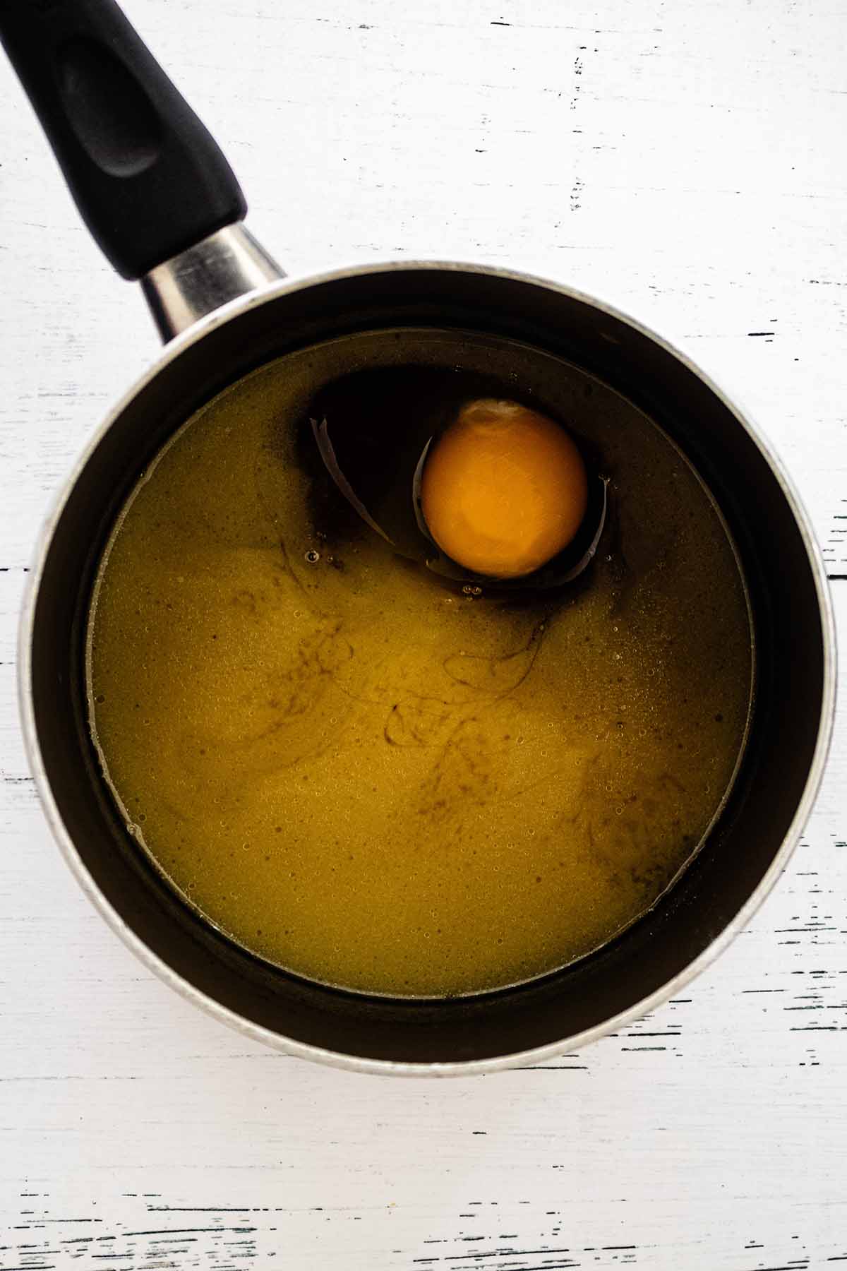 Egg in apple cider and butter mixture in a saucepan.