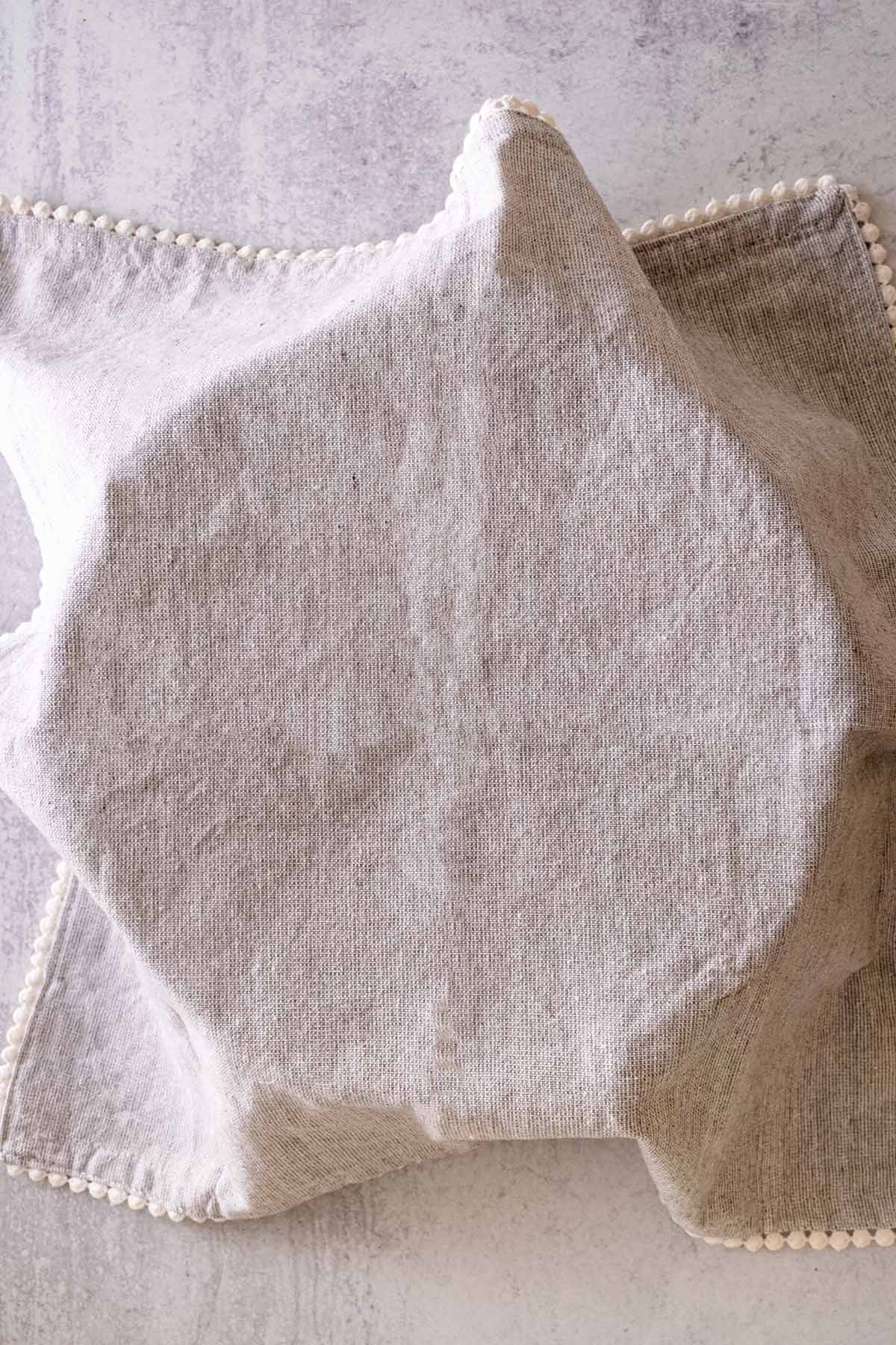 Dough covered with a light grey cloth napkin.
