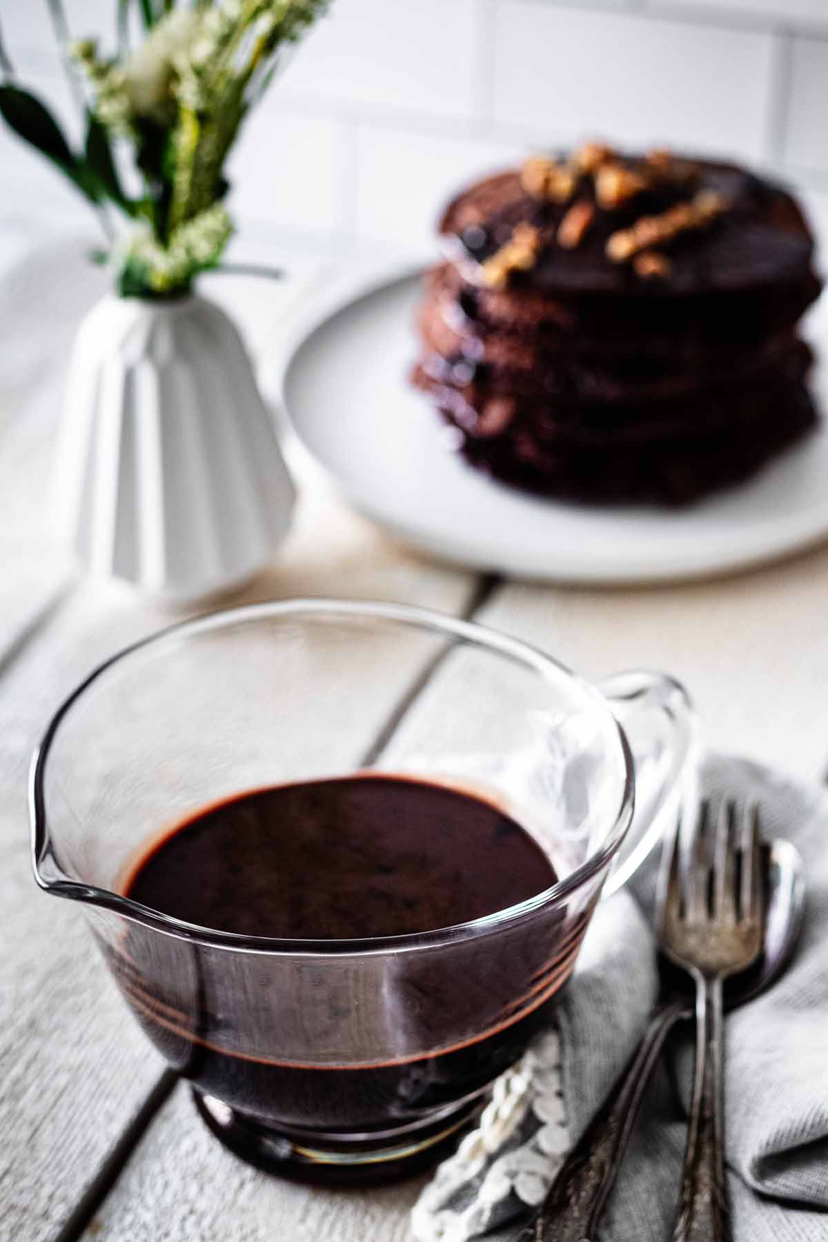 Chocolate pancake syrup in a small glass pitcher.