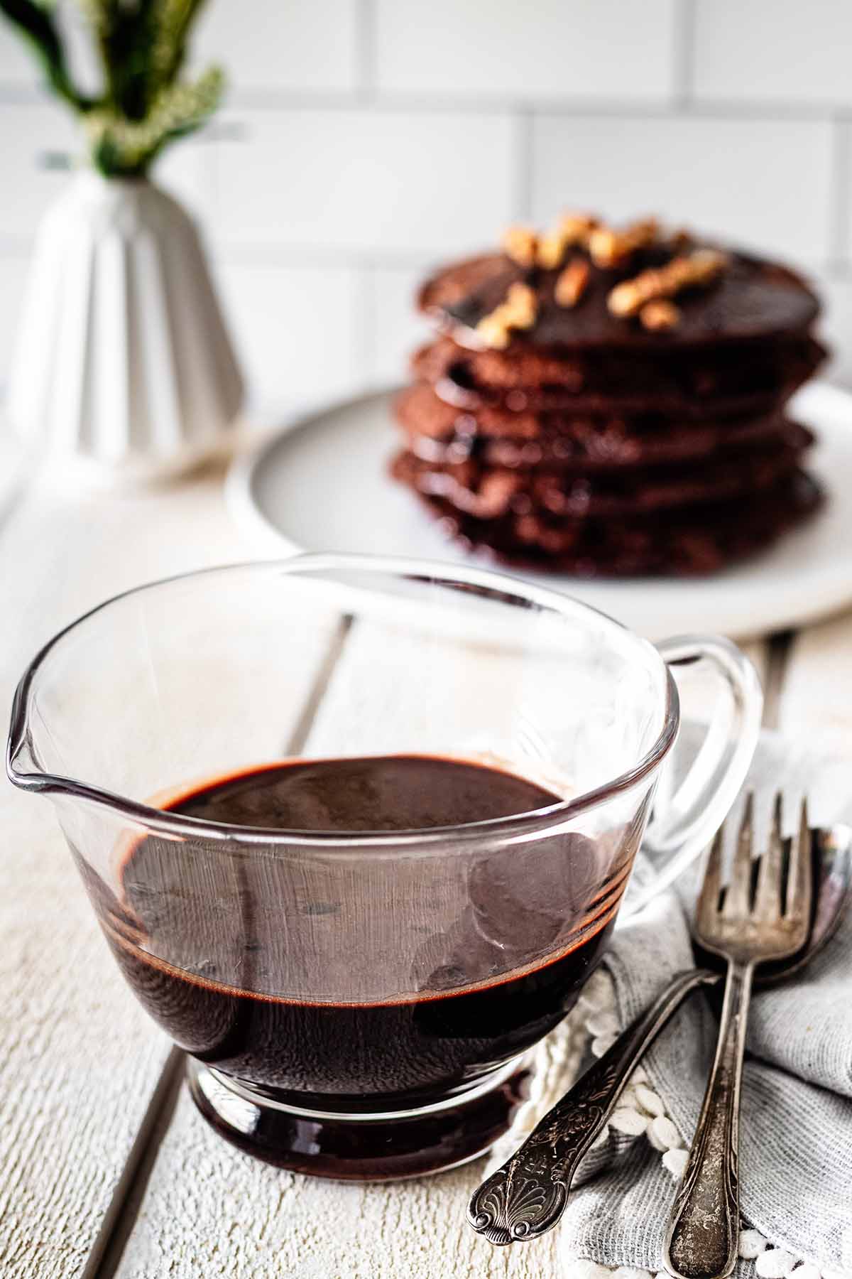 Chocolate pancake syrup in a small glass pitcher.