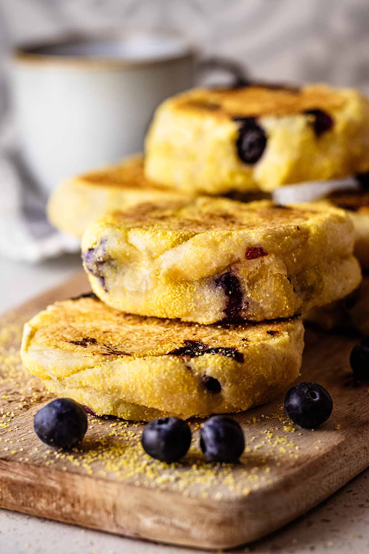 Stack of blueberry English muffins on a wooden cutting board.