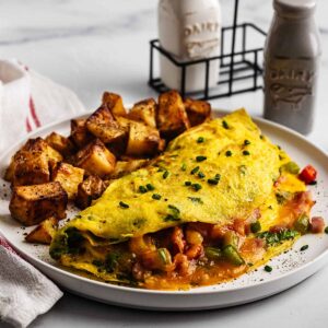Western omelette and roasted potatoes on a white plate.