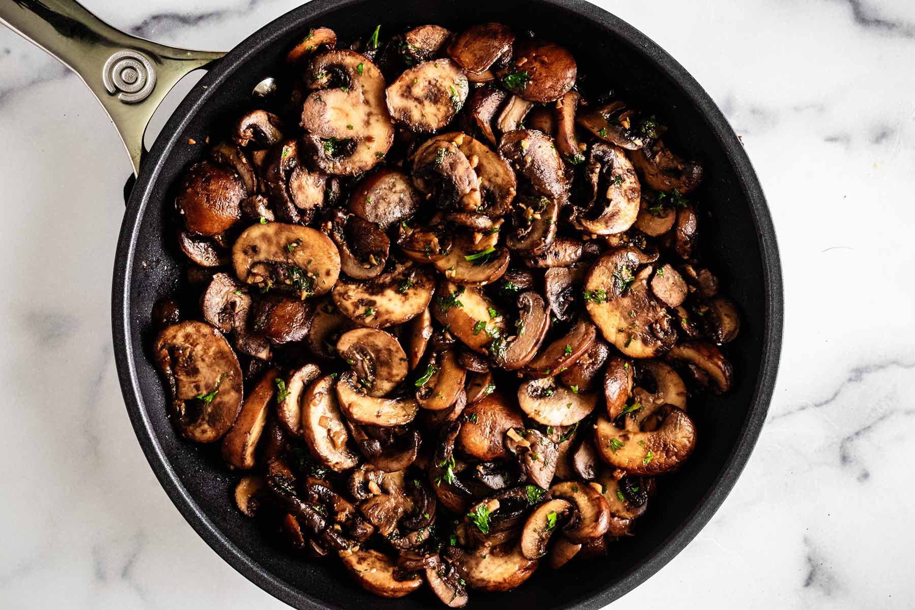Closeup of cooked mushrooms in a skillet.
