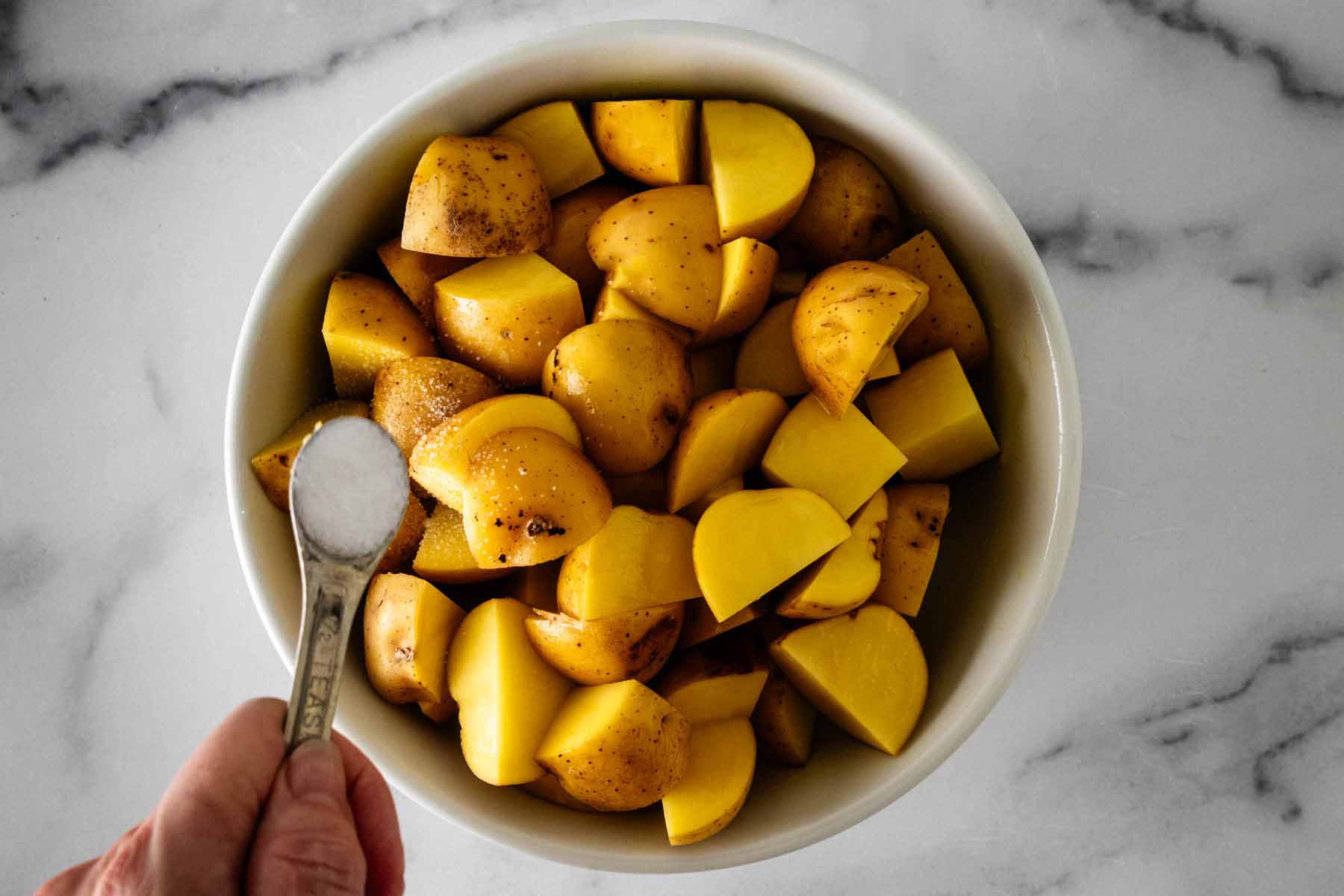 Add salt to chopped golden potatoes.
