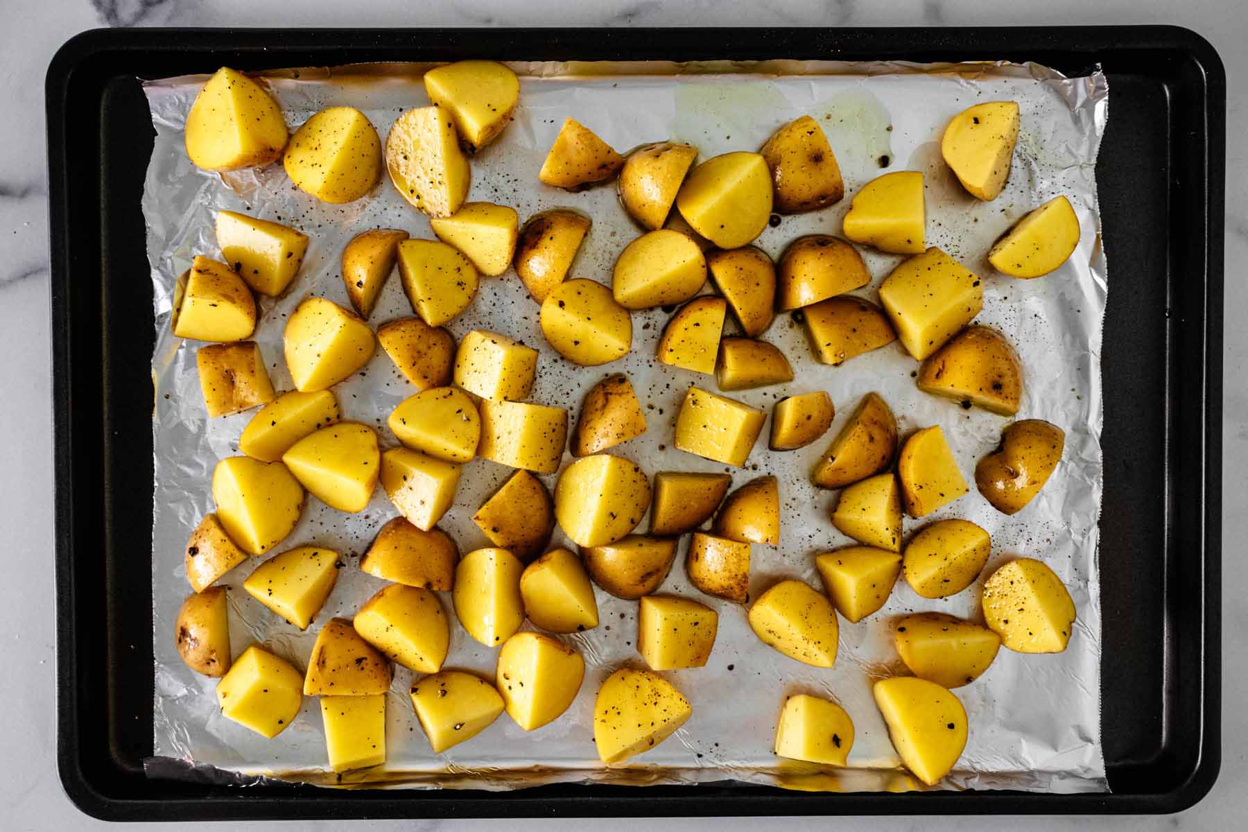 Chopped potatoes spread out onto a baking sheet lined with foil.