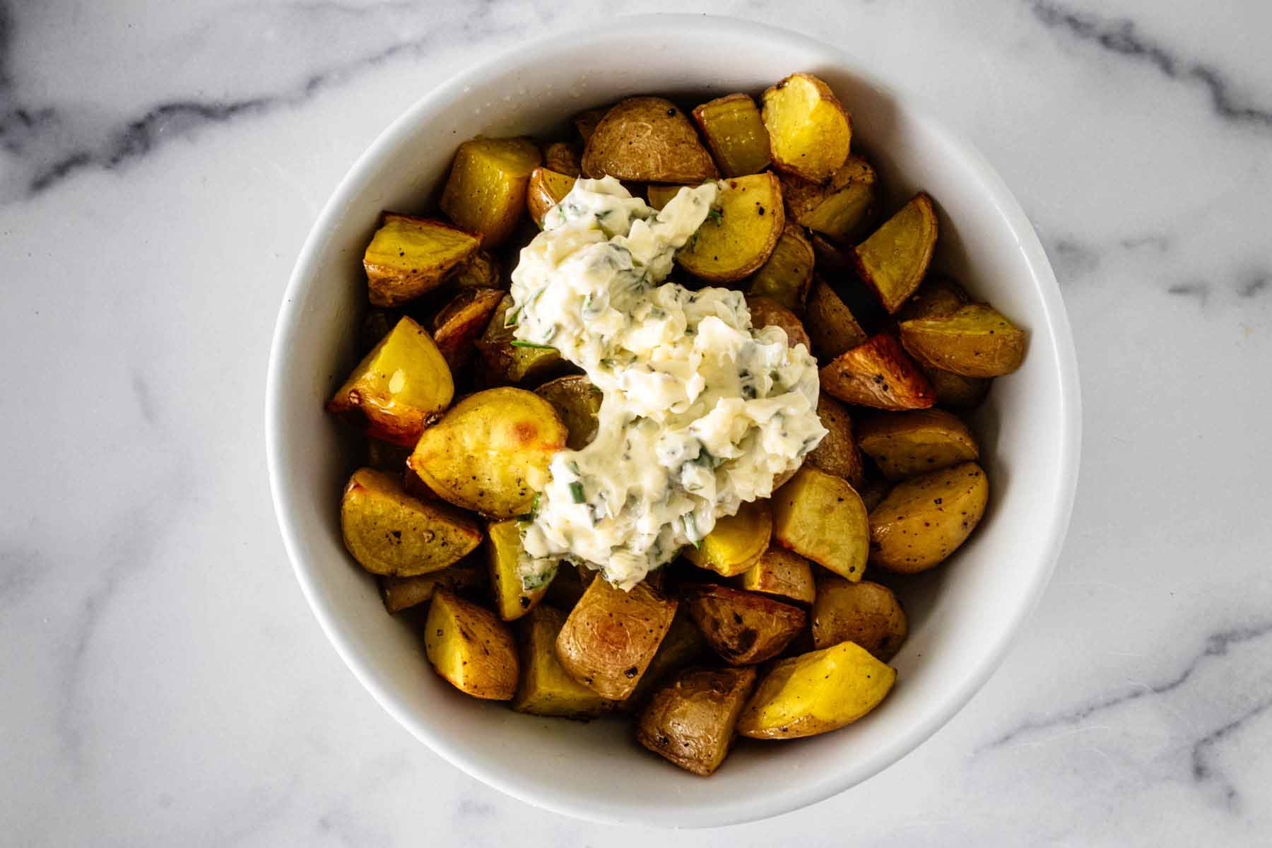 Garlic and rosemary butter mixes on top of roasted potatoes.